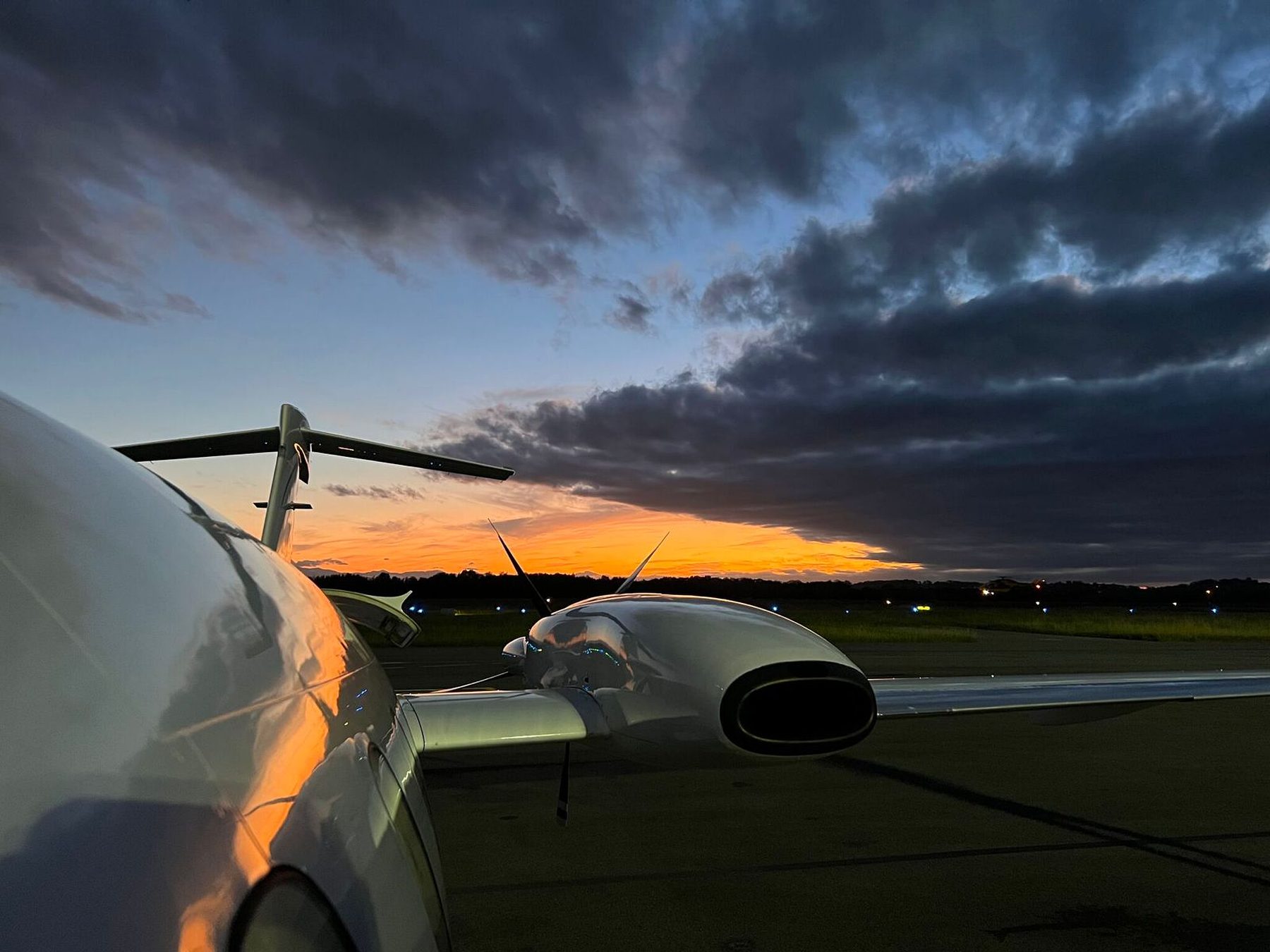Avanti wing, engine nacelle and pusher propeller silhouetted against a sunset ramp